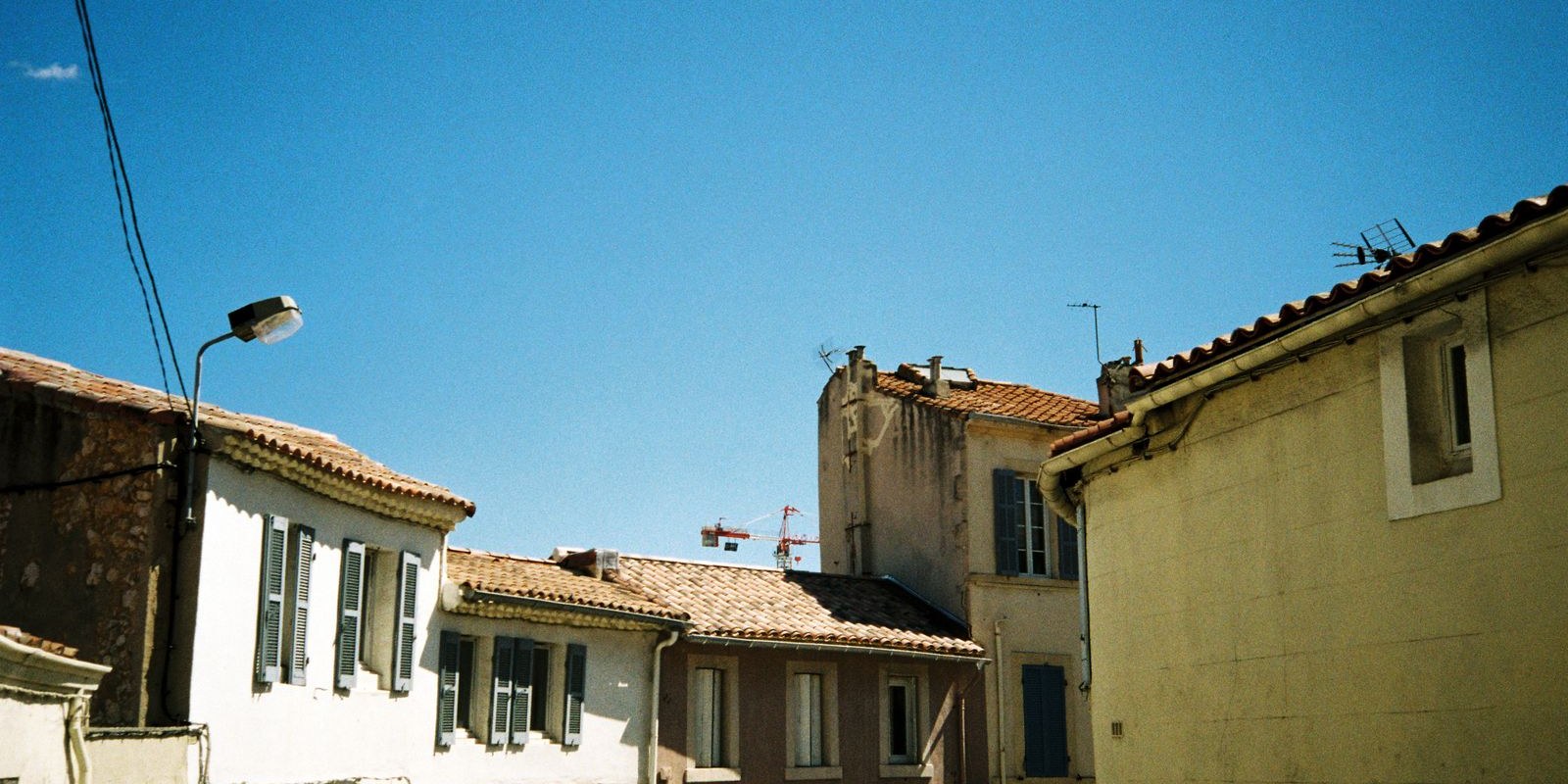 Toiture en tuiles canal et ciel bleu balayé par le mistral en Provence à Arles